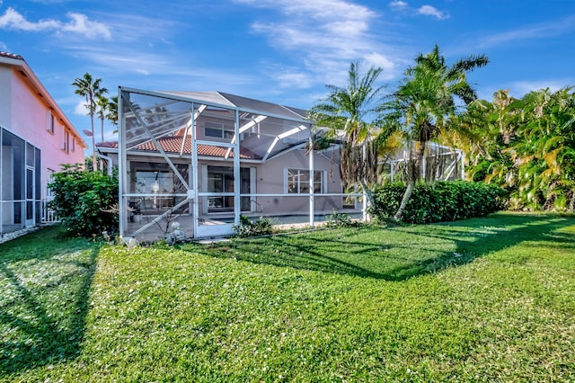 back of property featuring glass enclosure and a lawn