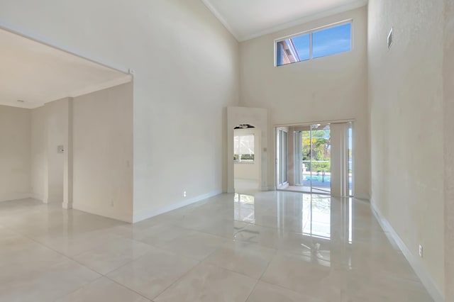 unfurnished room with visible vents, a high ceiling, baseboards, and crown molding