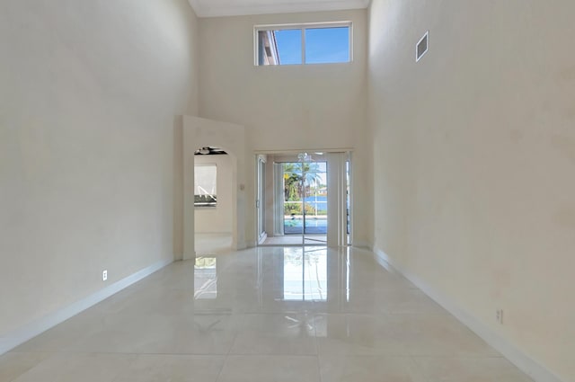 interior space with visible vents, a towering ceiling, and baseboards