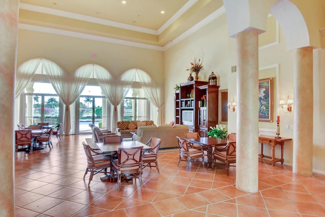 dining space featuring light tile patterned floors, arched walkways, a towering ceiling, ornamental molding, and decorative columns