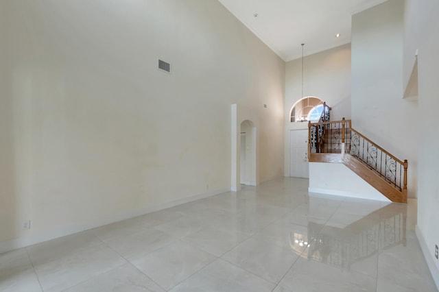 interior space featuring arched walkways, a towering ceiling, visible vents, stairs, and baseboards