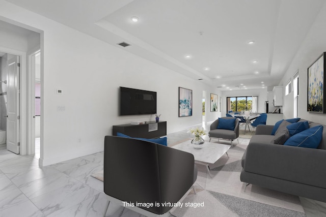 living area with baseboards, visible vents, marble finish floor, recessed lighting, and a tray ceiling