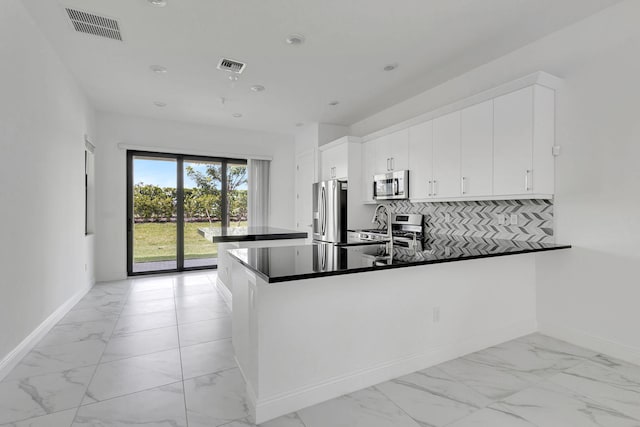 kitchen featuring dark countertops, visible vents, white cabinetry, stainless steel appliances, and a peninsula