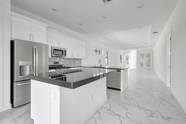 kitchen featuring white cabinets, dark countertops, a kitchen island, and stainless steel appliances