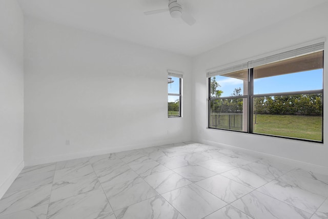 empty room featuring baseboards, marble finish floor, and a ceiling fan