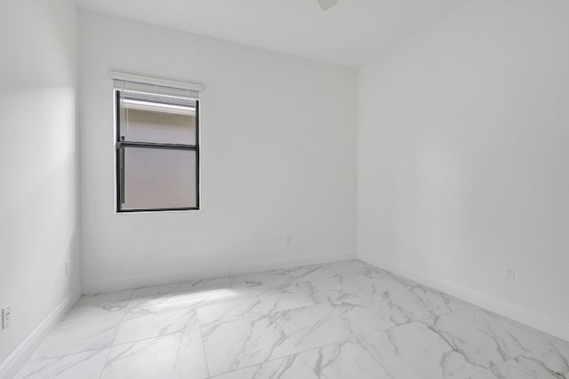 spare room featuring baseboards and marble finish floor