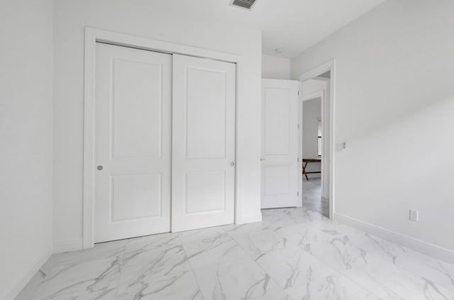 unfurnished bedroom featuring marble finish floor, baseboards, a closet, and visible vents