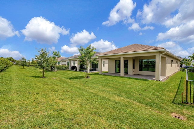 rear view of property with stucco siding, a patio area, and a yard