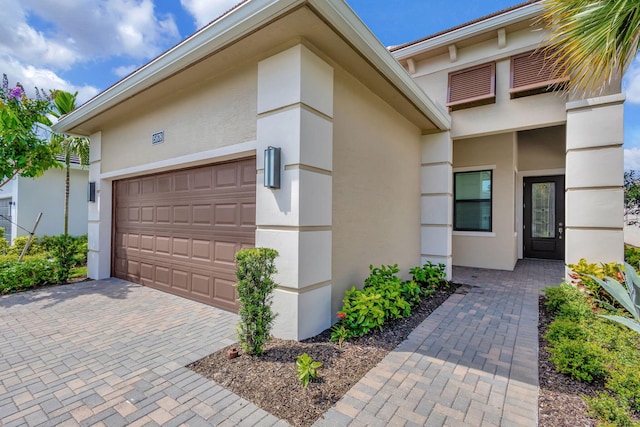 exterior space with stucco siding, decorative driveway, and a garage