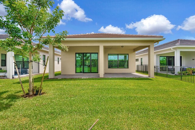 rear view of house with fence, stucco siding, a lawn, and a patio area