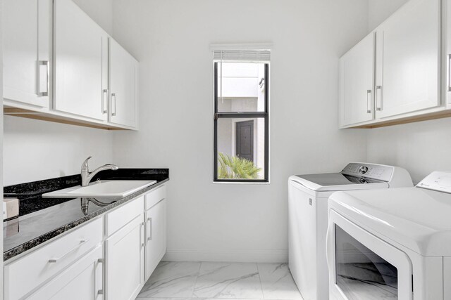 washroom with marble finish floor, cabinet space, washer and dryer, baseboards, and a sink