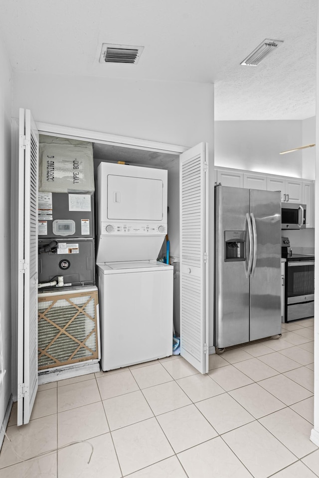 washroom with light tile patterned floors and stacked washer and dryer