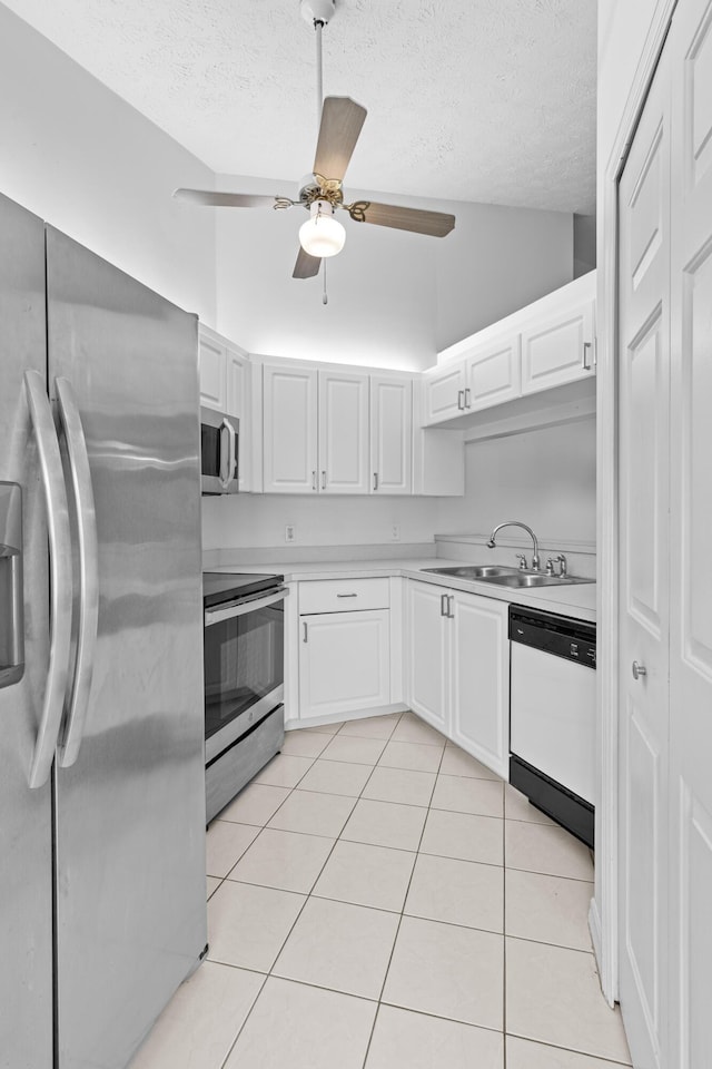 kitchen featuring appliances with stainless steel finishes, light tile patterned floors, sink, and white cabinetry