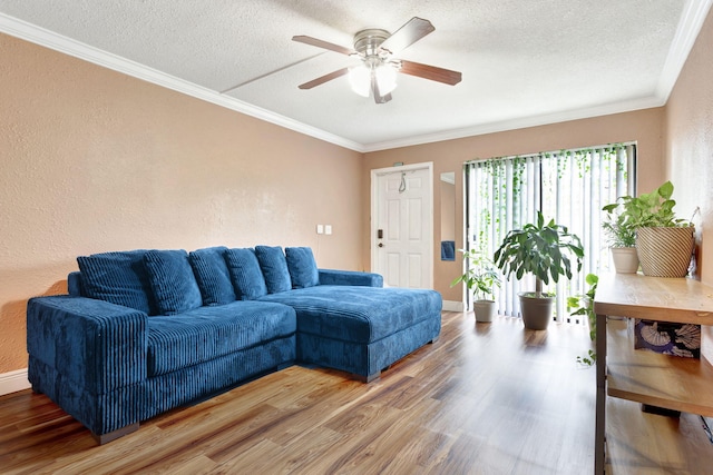 living area with a textured ceiling, ceiling fan, wood finished floors, baseboards, and ornamental molding