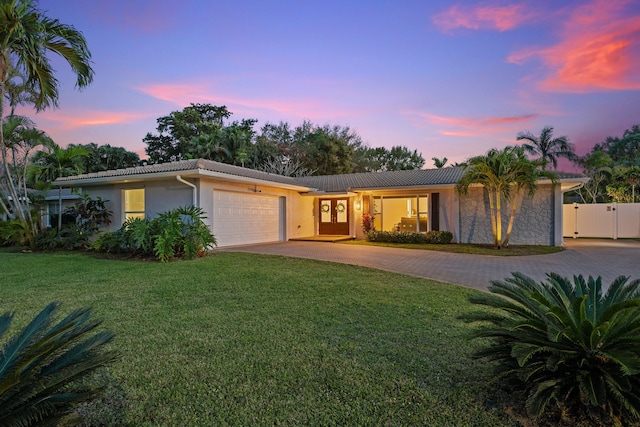 single story home with a tiled roof, an attached garage, decorative driveway, a front lawn, and stucco siding