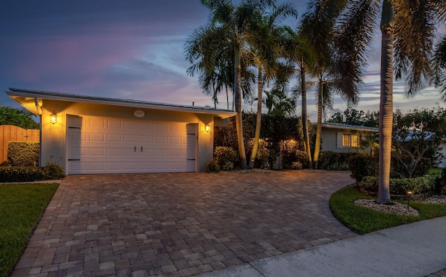 ranch-style home with an attached garage and decorative driveway