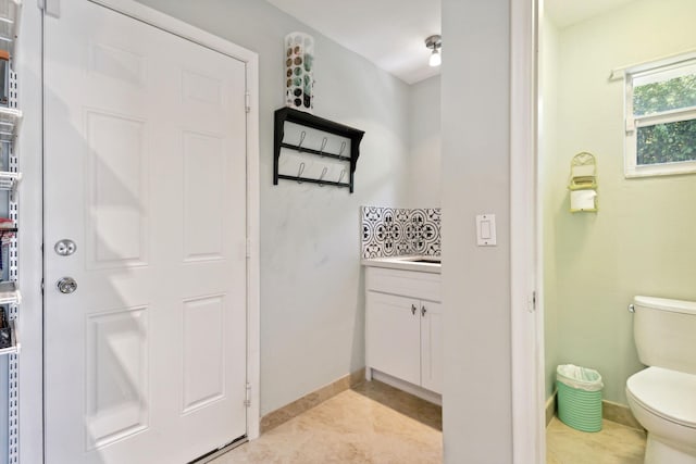 bathroom with toilet, vanity, baseboards, and tile patterned floors