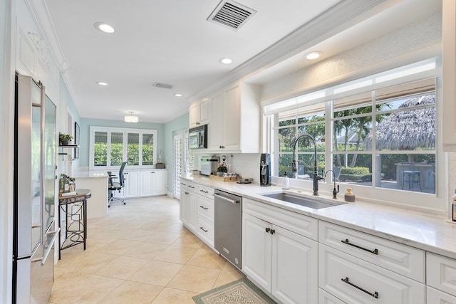 kitchen featuring visible vents, a sink, ornamental molding, stainless steel appliances, and white cabinets