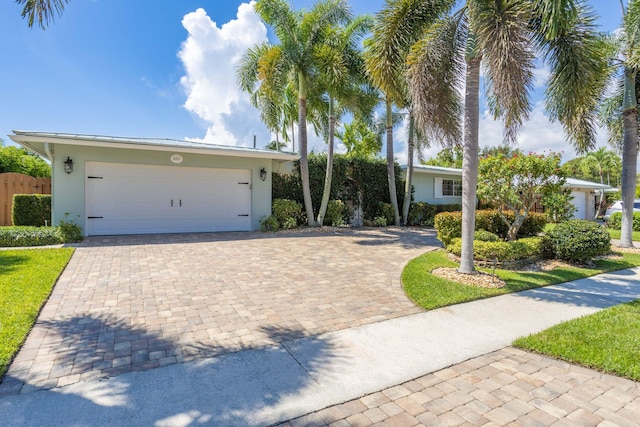 ranch-style house with a garage, decorative driveway, and stucco siding