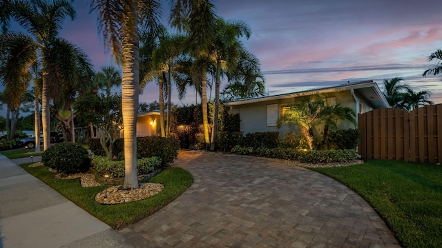view of front of property featuring a front yard, decorative driveway, fence, and stucco siding