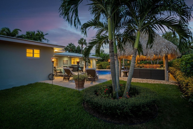 yard at dusk with an outdoor pool and a patio