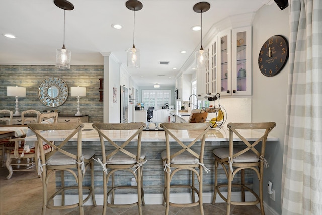 kitchen featuring stainless steel fridge, visible vents, an accent wall, glass insert cabinets, and recessed lighting