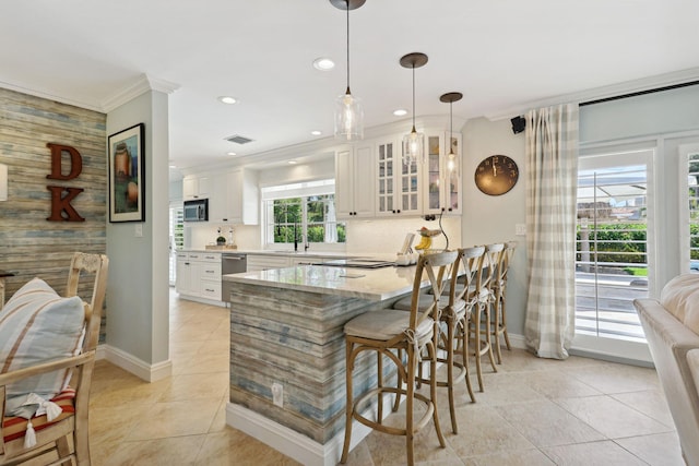 kitchen featuring light stone countertops, glass insert cabinets, white cabinets, and decorative light fixtures