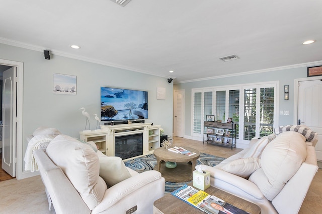 living room featuring visible vents, a glass covered fireplace, and crown molding