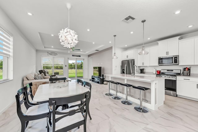 dining area featuring recessed lighting, a raised ceiling, visible vents, and a healthy amount of sunlight