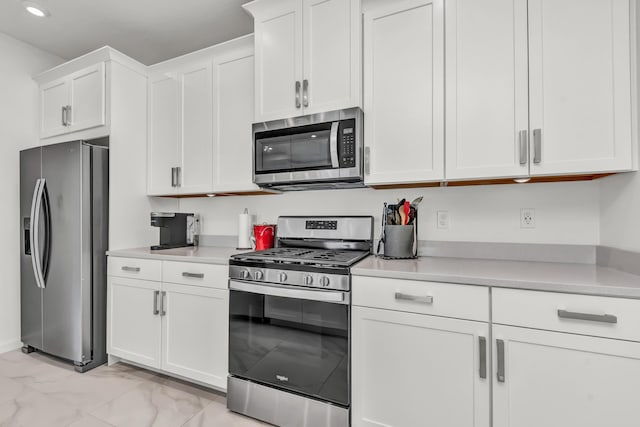 kitchen featuring appliances with stainless steel finishes, marble finish floor, light countertops, and white cabinets