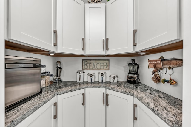 kitchen with white cabinetry and light stone countertops