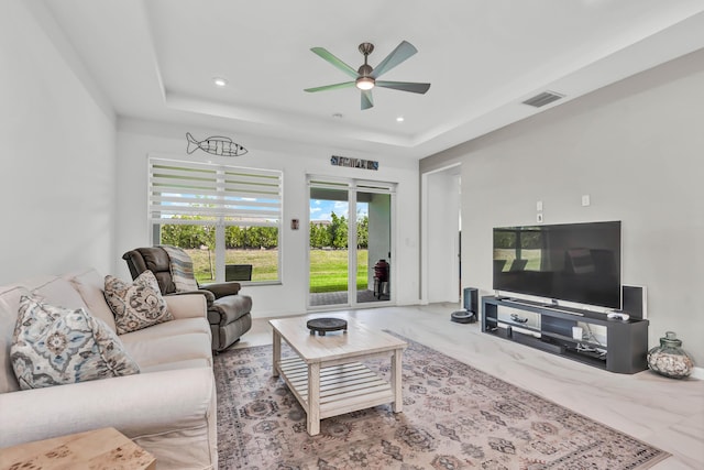 living room with marble finish floor, a tray ceiling, visible vents, and recessed lighting