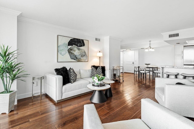 living room with a chandelier, dark wood-type flooring, and ornamental molding