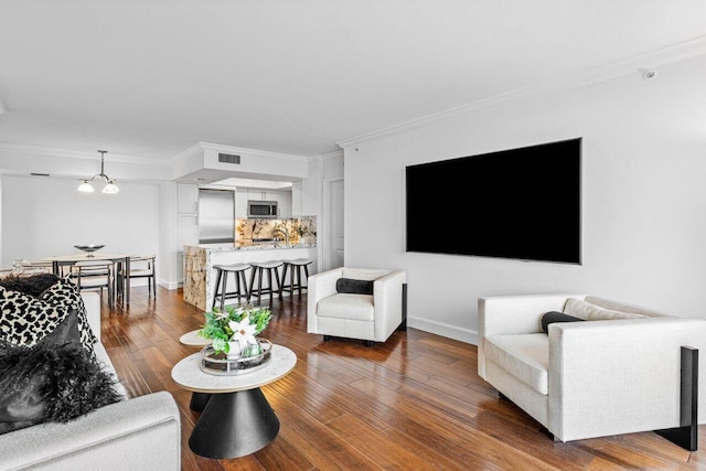 living room featuring ornamental molding, hardwood / wood-style flooring, and a notable chandelier