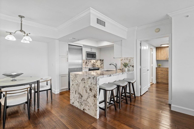 kitchen with light stone countertops, pendant lighting, sink, white cabinetry, and kitchen peninsula