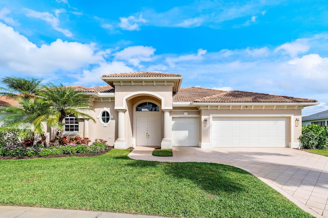 mediterranean / spanish house featuring decorative driveway, a front yard, an attached garage, and stucco siding