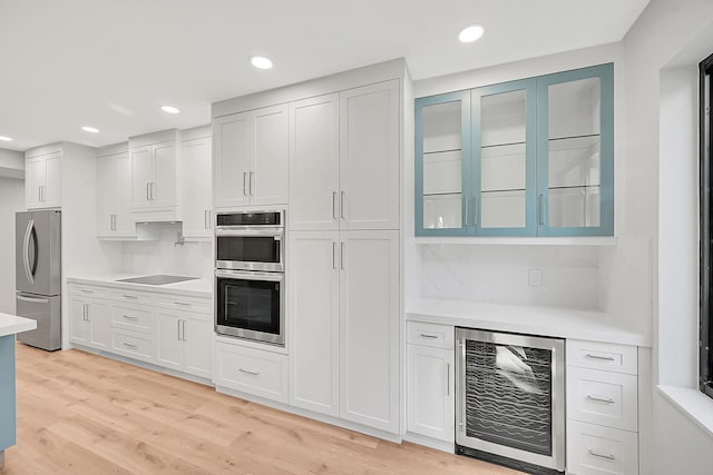 303 Sea Oats Dr Unit D, Juno Beach, FL 33408 - kitchen featuring beverage cooler, light countertops, stainless steel appliances, light wood-type flooring, and white cabinetry