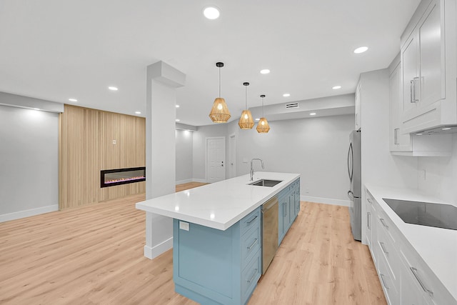 303 Sea Oats Dr Unit D, Juno Beach, FL 33408 - kitchen featuring stainless steel appliances, a sink, a kitchen island with sink, a glass covered fireplace, and blue cabinetry