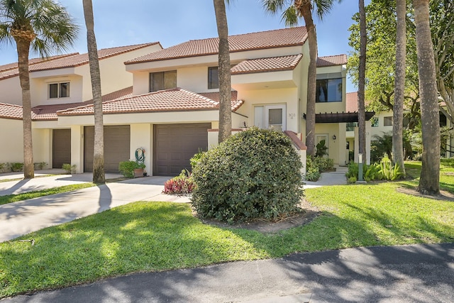 view of property featuring driveway, a front yard, an attached garage, and stucco siding