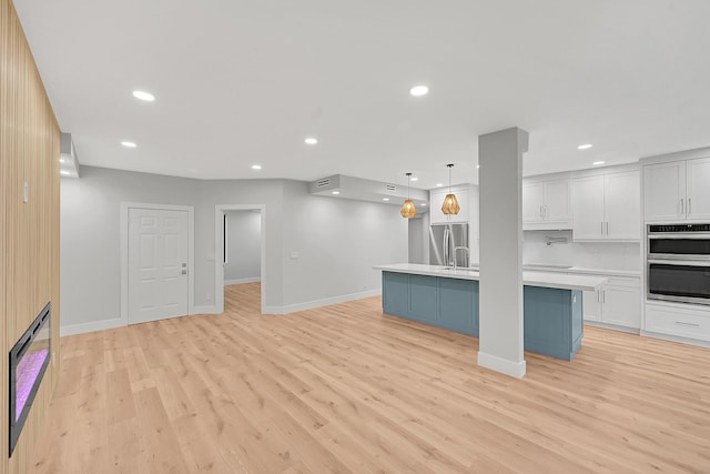 303 Sea Oats Dr Unit D, Juno Beach, FL 33408 - unfurnished living room with recessed lighting, light wood finished floors, baseboards, and a sink