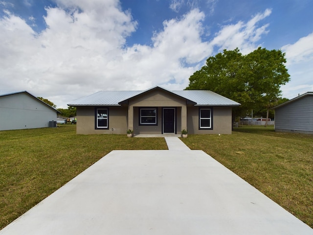 ranch-style house with metal roof, a front lawn, and stucco siding