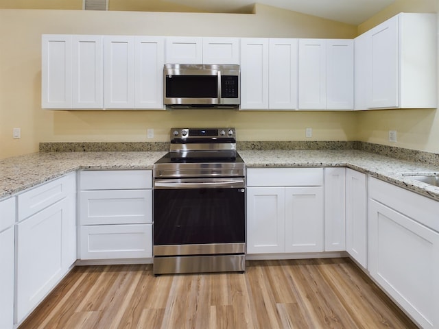 kitchen with light stone countertops, light wood-style flooring, white cabinetry, and stainless steel appliances