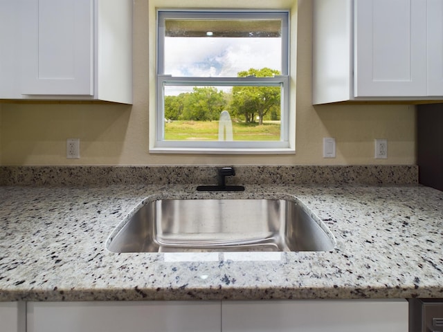 interior details featuring light stone countertops, white cabinetry, and a sink