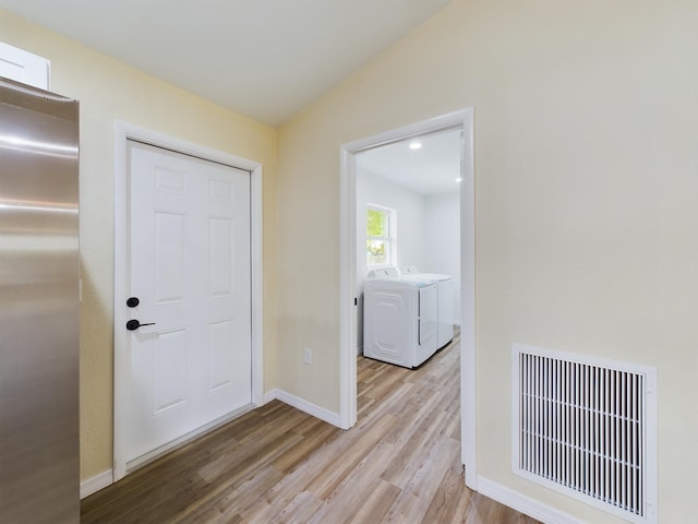 interior space with washing machine and clothes dryer, visible vents, vaulted ceiling, light wood-type flooring, and baseboards