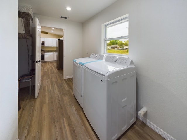 washroom featuring laundry area, separate washer and dryer, dark wood-style flooring, and baseboards