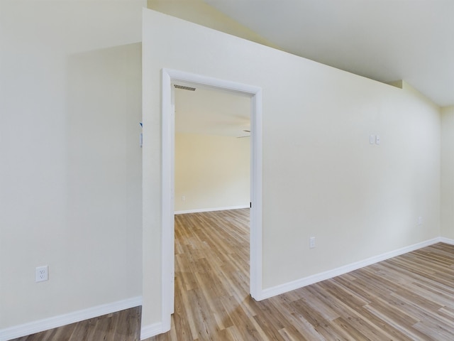 empty room with light wood finished floors, visible vents, and baseboards