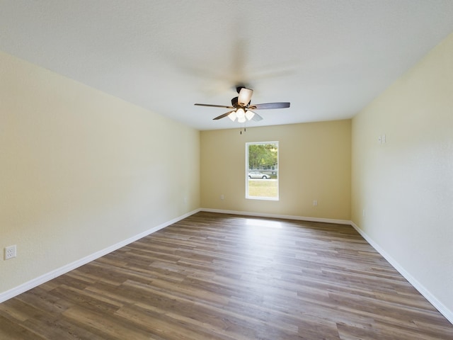 spare room featuring ceiling fan, baseboards, and wood finished floors