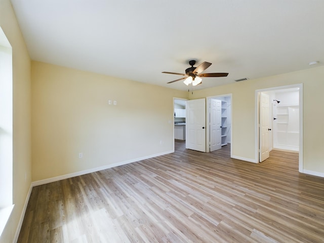 unfurnished bedroom featuring baseboards, visible vents, a spacious closet, and light wood finished floors