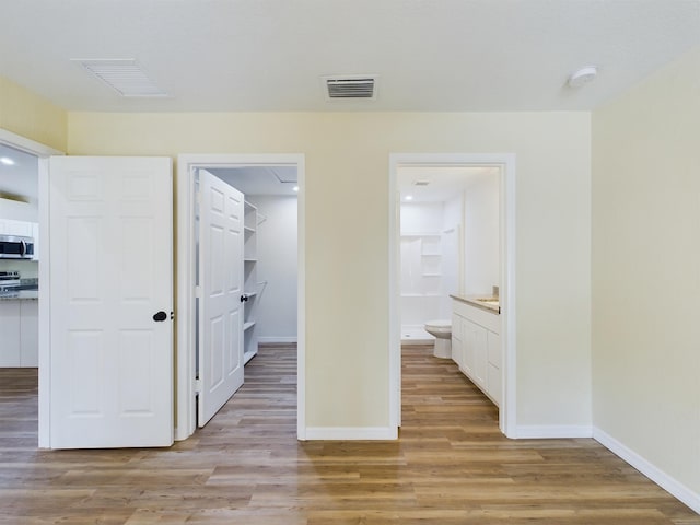 unfurnished bedroom with light wood-style floors, a spacious closet, visible vents, and a closet