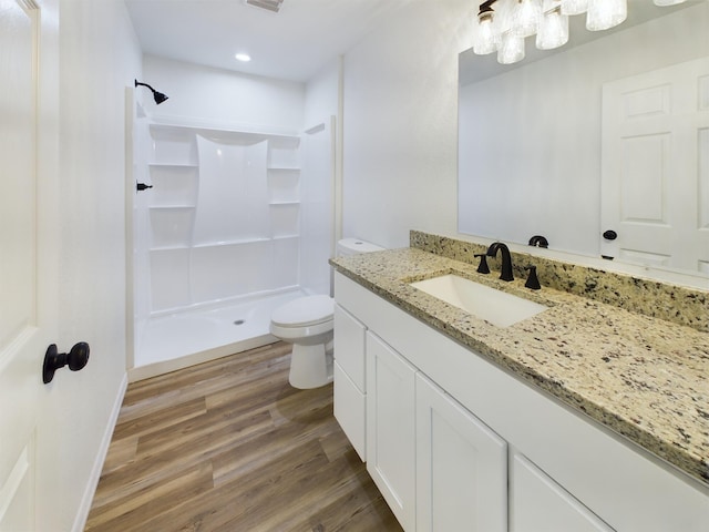 bathroom with toilet, wood finished floors, visible vents, vanity, and a stall shower